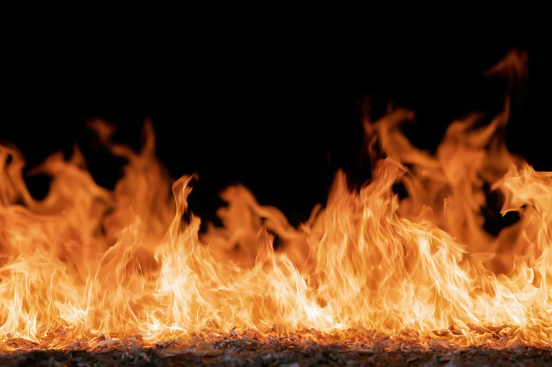 Intense flames burning across a dark surface in close-up view