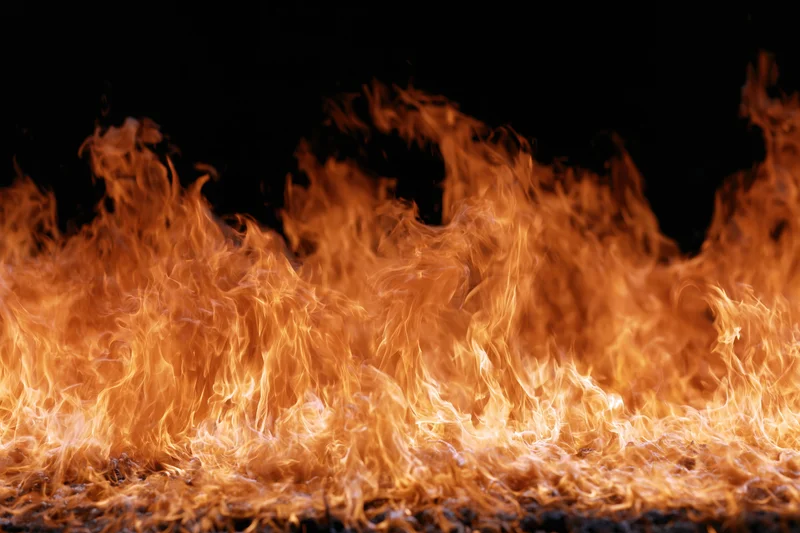 Close-up of intense orange and yellow flames burning against a dark background