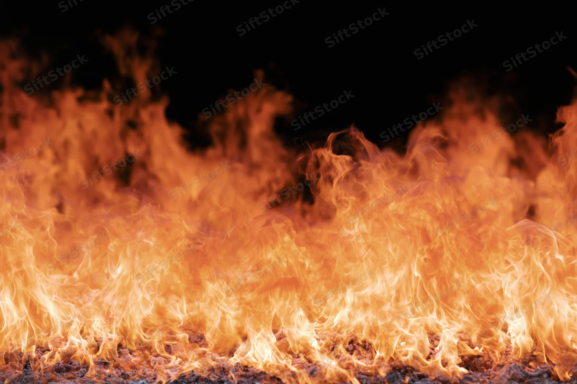 Close-up of intense flames burning across a dark surface