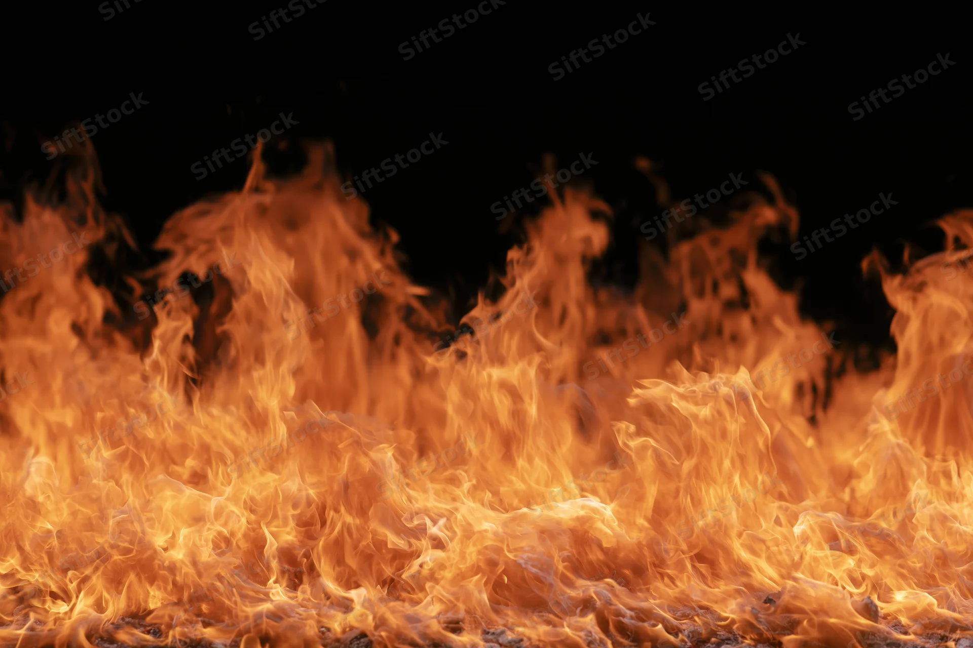 Intense flames burning across the frame against a black background
