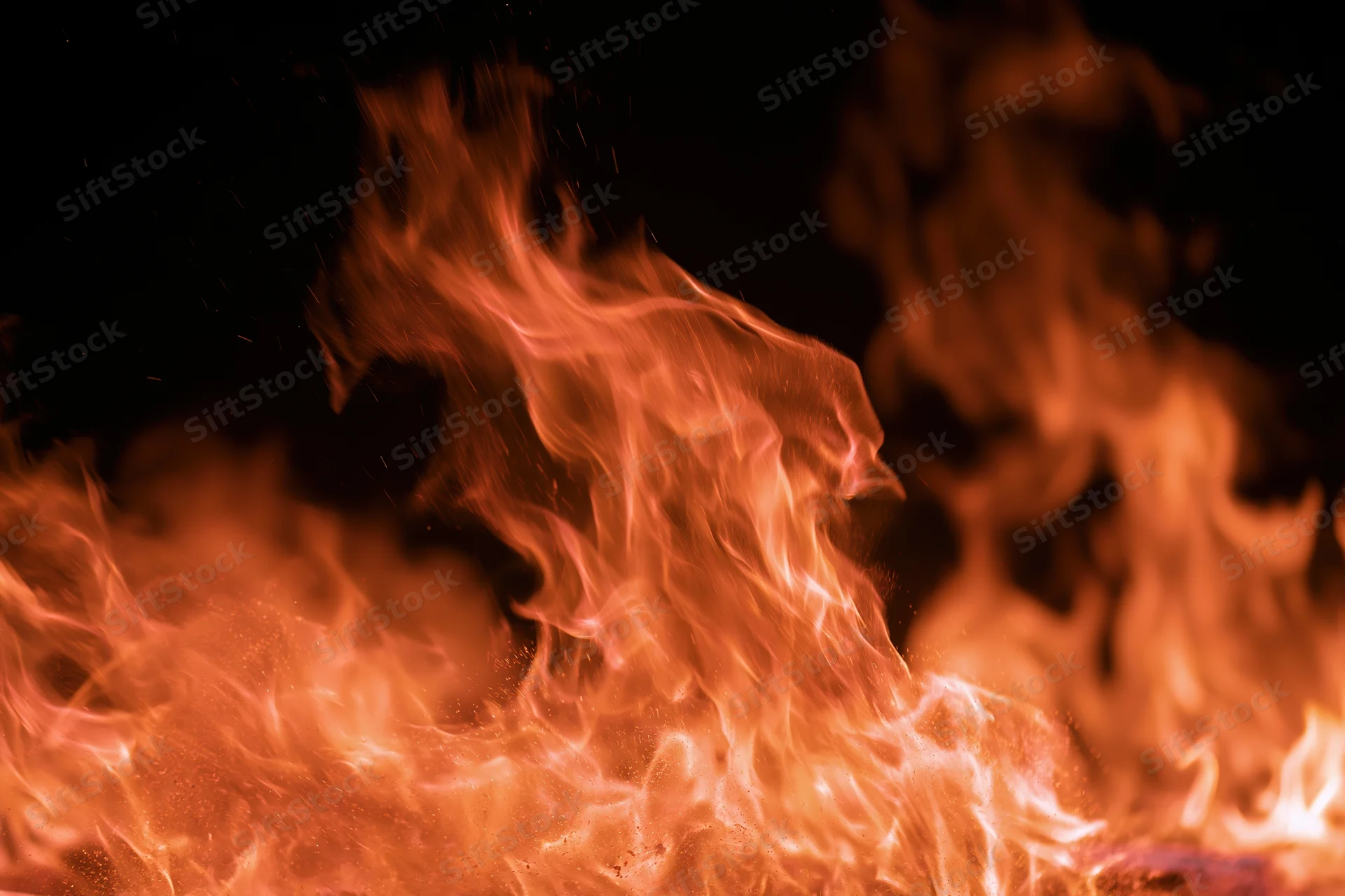 Large open flames filling the frame with tongues of fire rising against a dark background