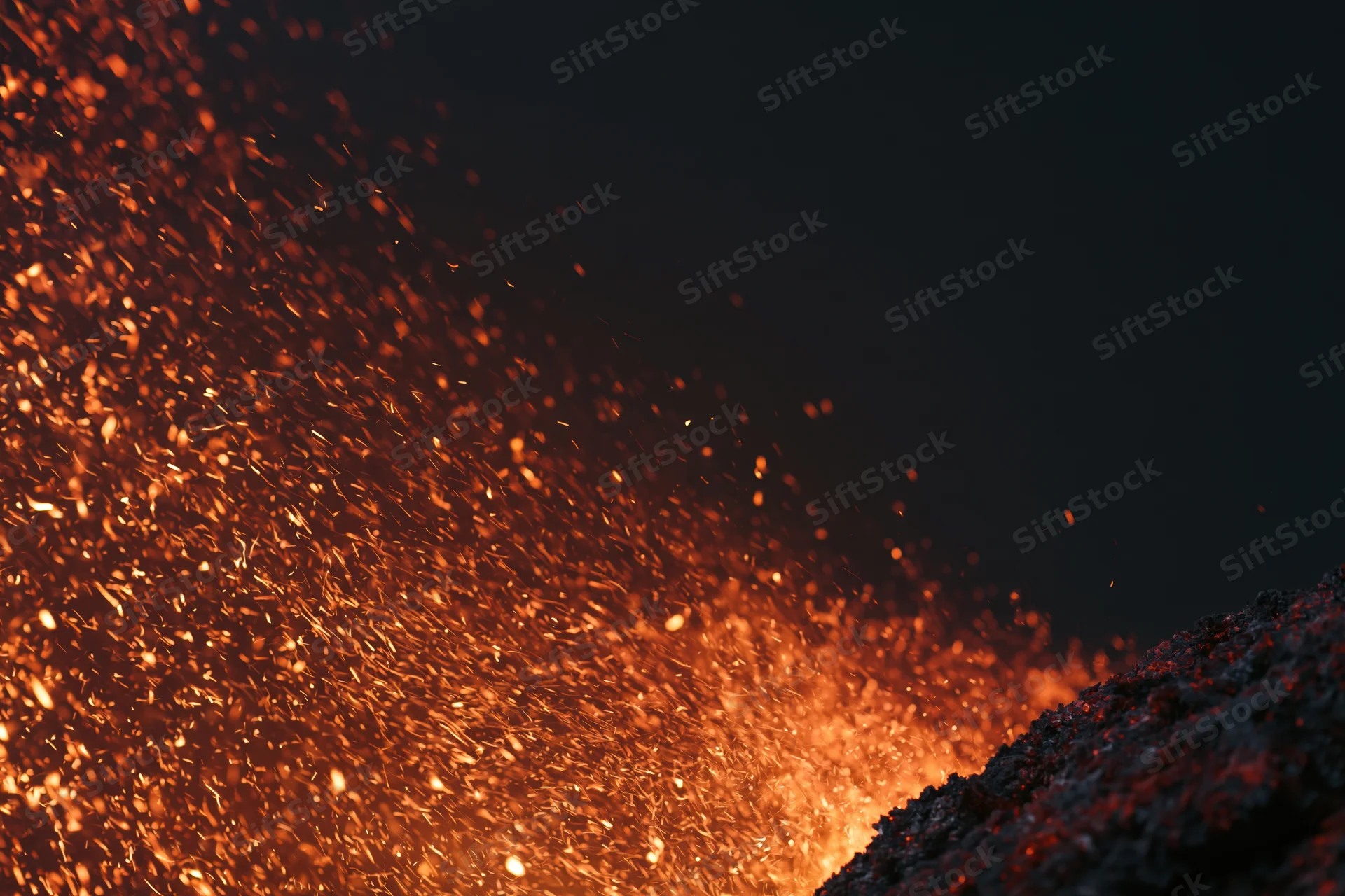 Glowing embers and sparks flying from a fiery source at night