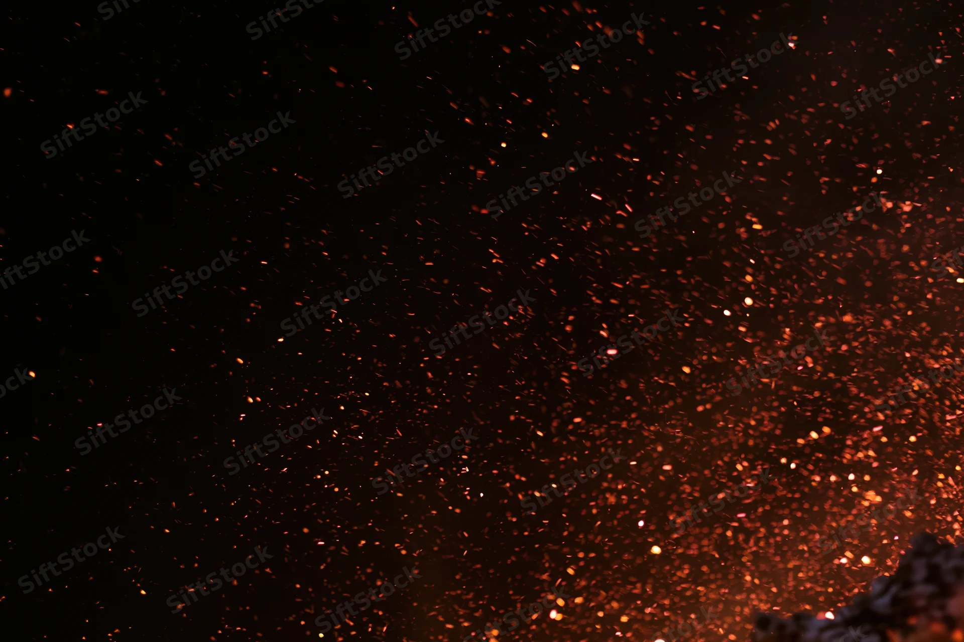 Glowing embers and sparks rising into the dark night sky