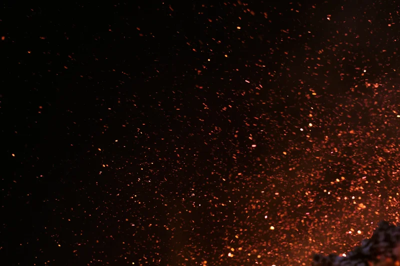 Glowing embers and sparks rising into the dark night sky