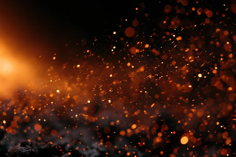 Glowing embers and sparks flying through dark air at night