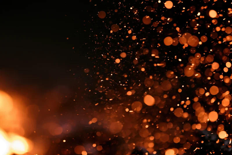 Glowing sparks and embers floating in dark night air