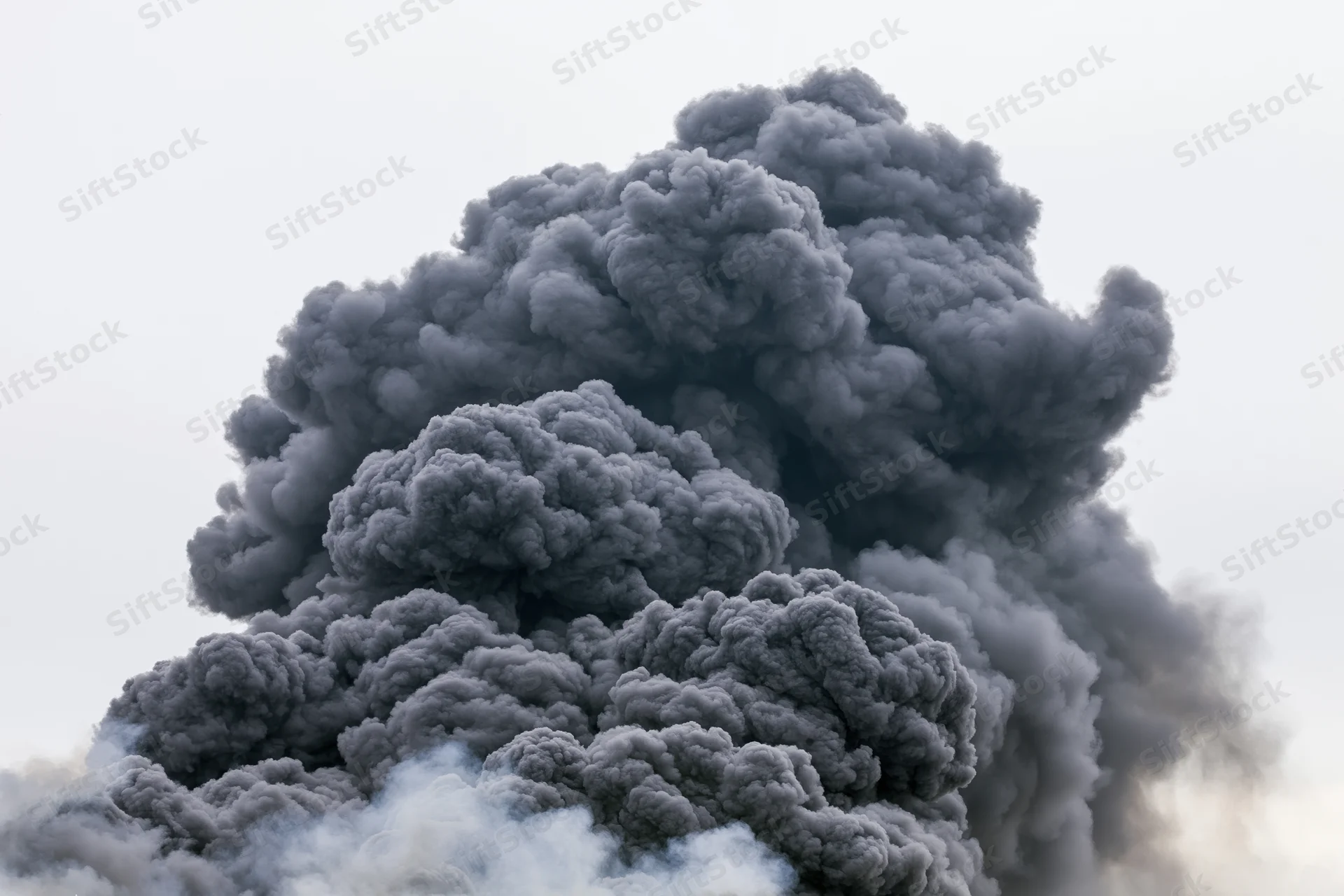 Massive billowing column of dark grey smoke rising into the sky