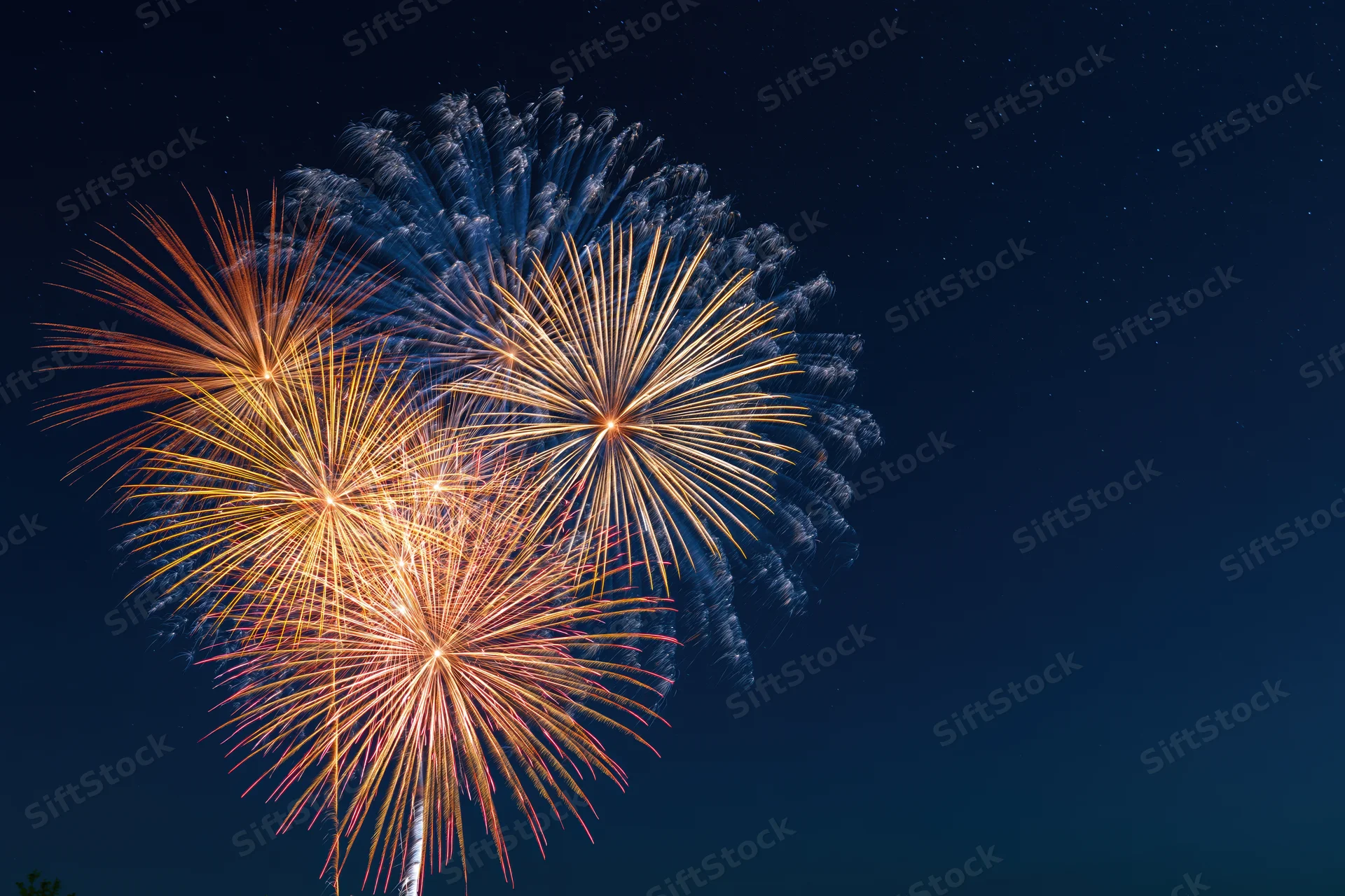 Fireworks bursting in the night sky with colorful trails and smoke against a dark starry background