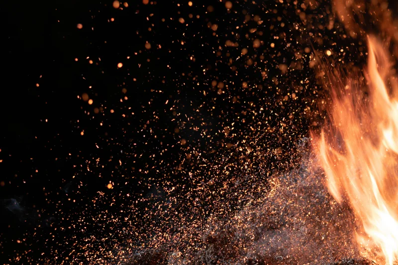 Fire burning with sparks and embers flying upward against dark background