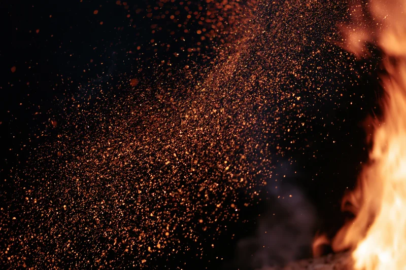 Fire burning with sparks and embers flying upward against dark background