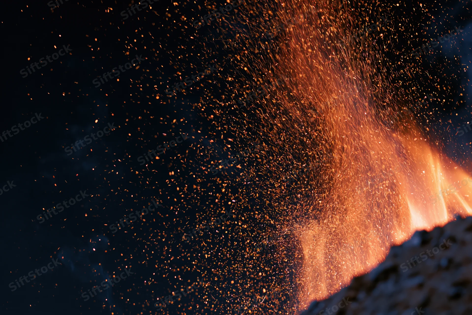 Fire burning with sparks and embers flying upward at night outdoors