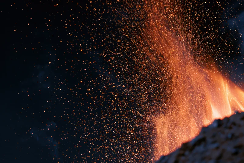 Fire burning with sparks and embers flying upward at night outdoors