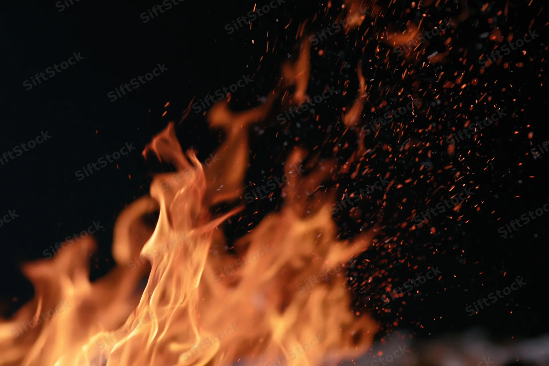 Flames burning with sparks against a black background