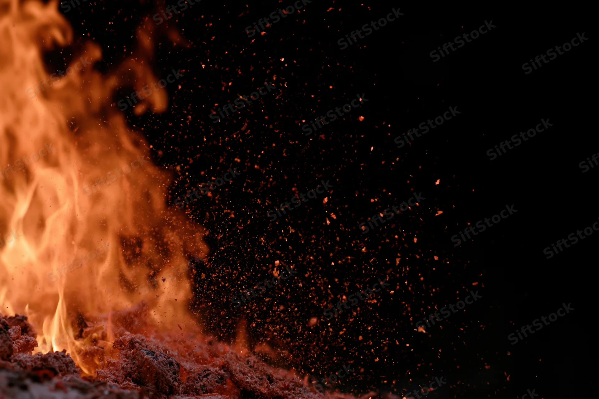 Flames burning with flying sparks against a black background