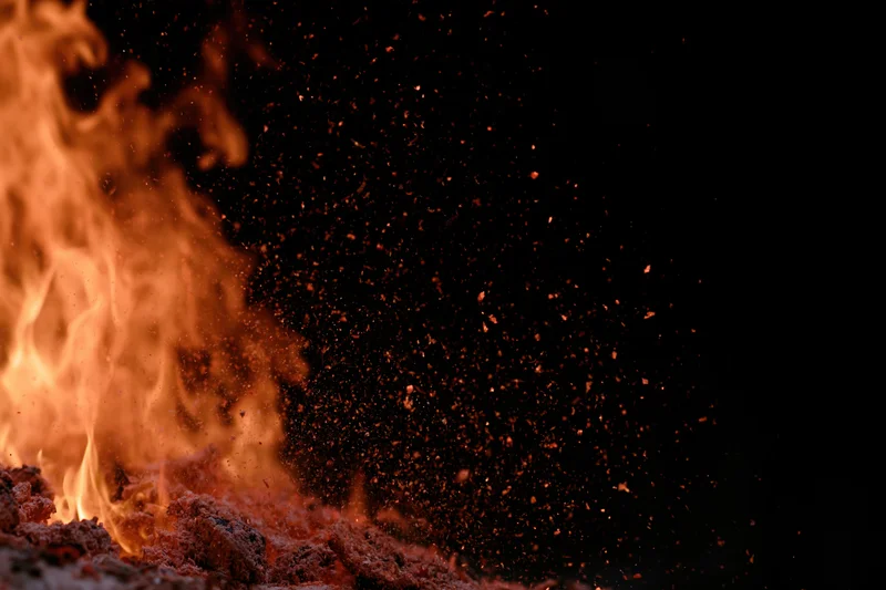 Flames burning with flying sparks against a black background