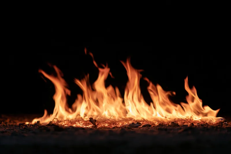Low flames burning across a dark ground surface at night