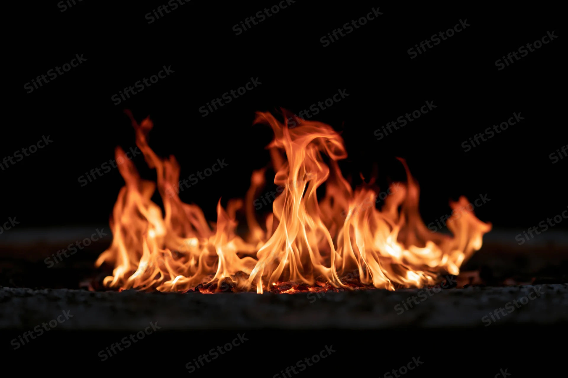 Flames burning low against a black background