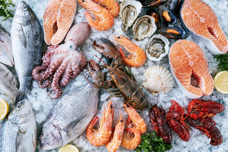 Overhead flat-lay of fresh seafood arranged on ice with lemon and parsley