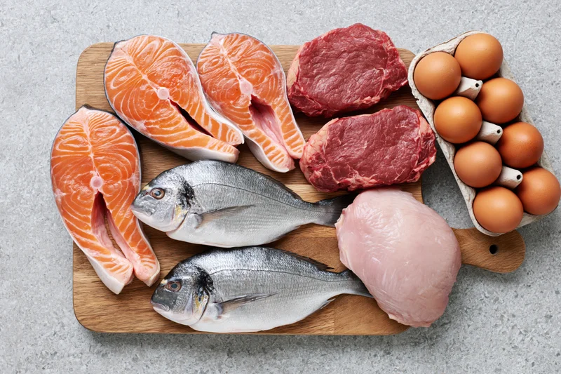 Raw protein foods arranged flat lay on light gray stone surface