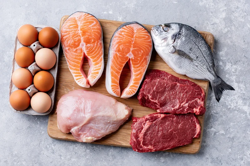 Raw protein foods arranged flat lay on light gray stone surface