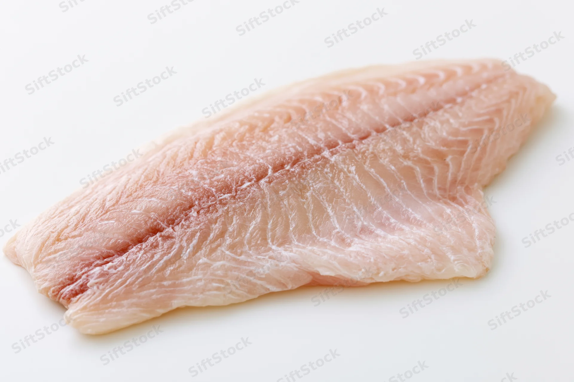Raw white fish fillet laid flat on white background