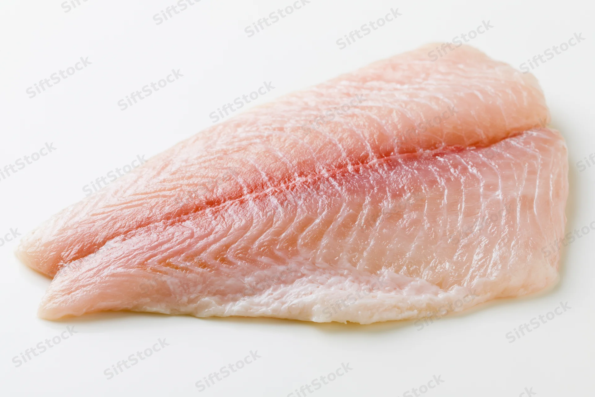 Raw white fish fillet laid flat on white surface