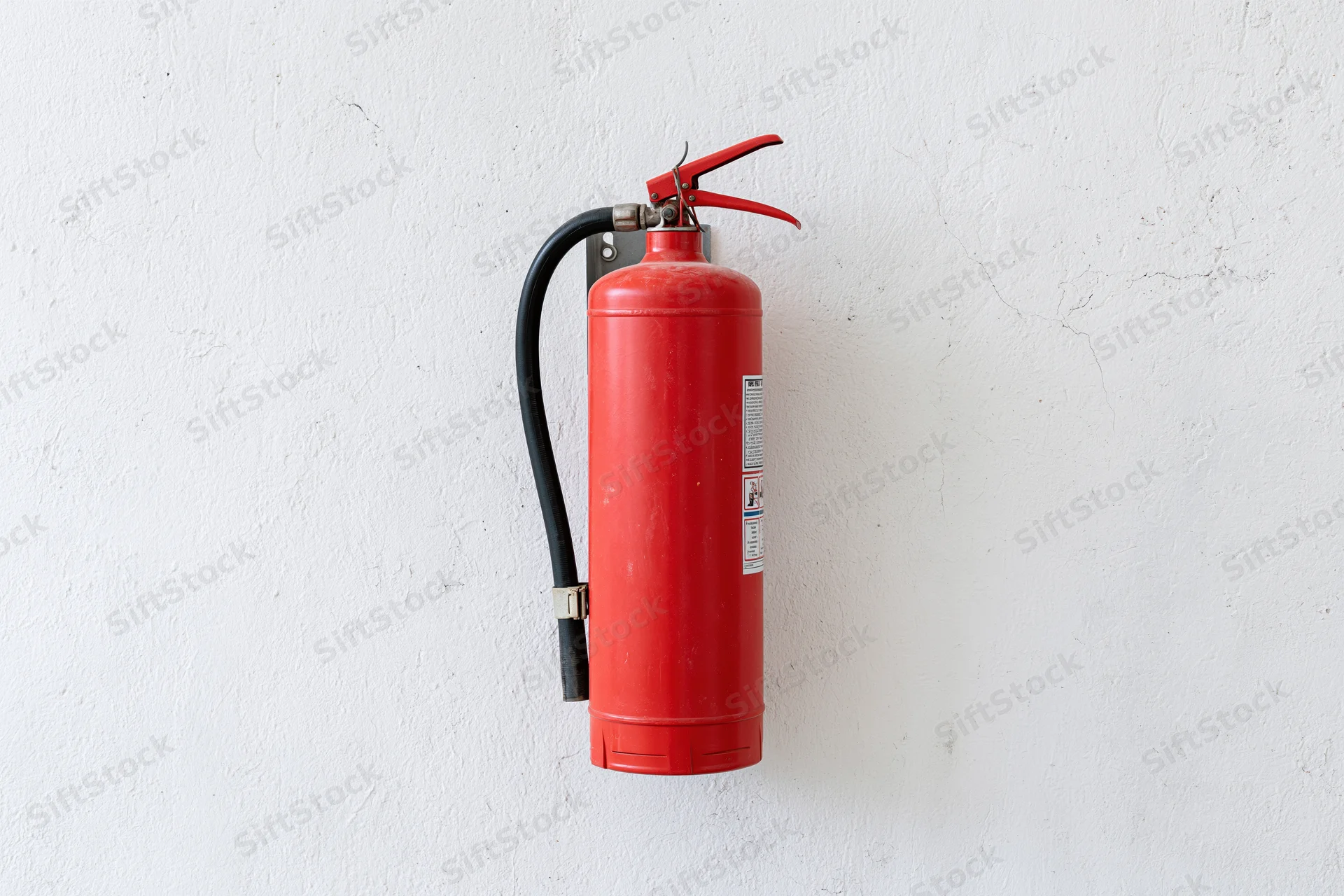 Red fire extinguisher mounted on a white textured wall