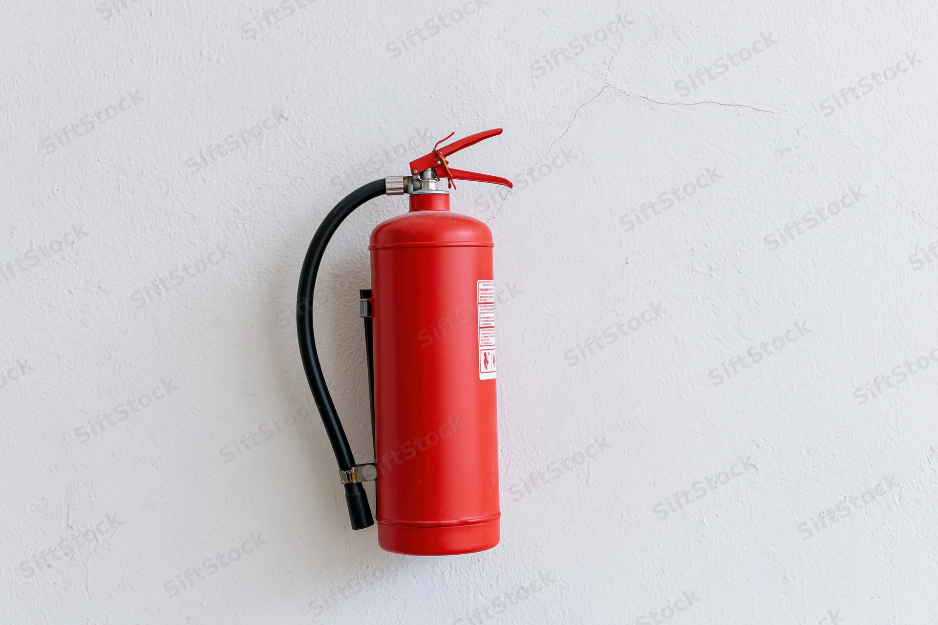 Red fire extinguisher mounted on a white wall