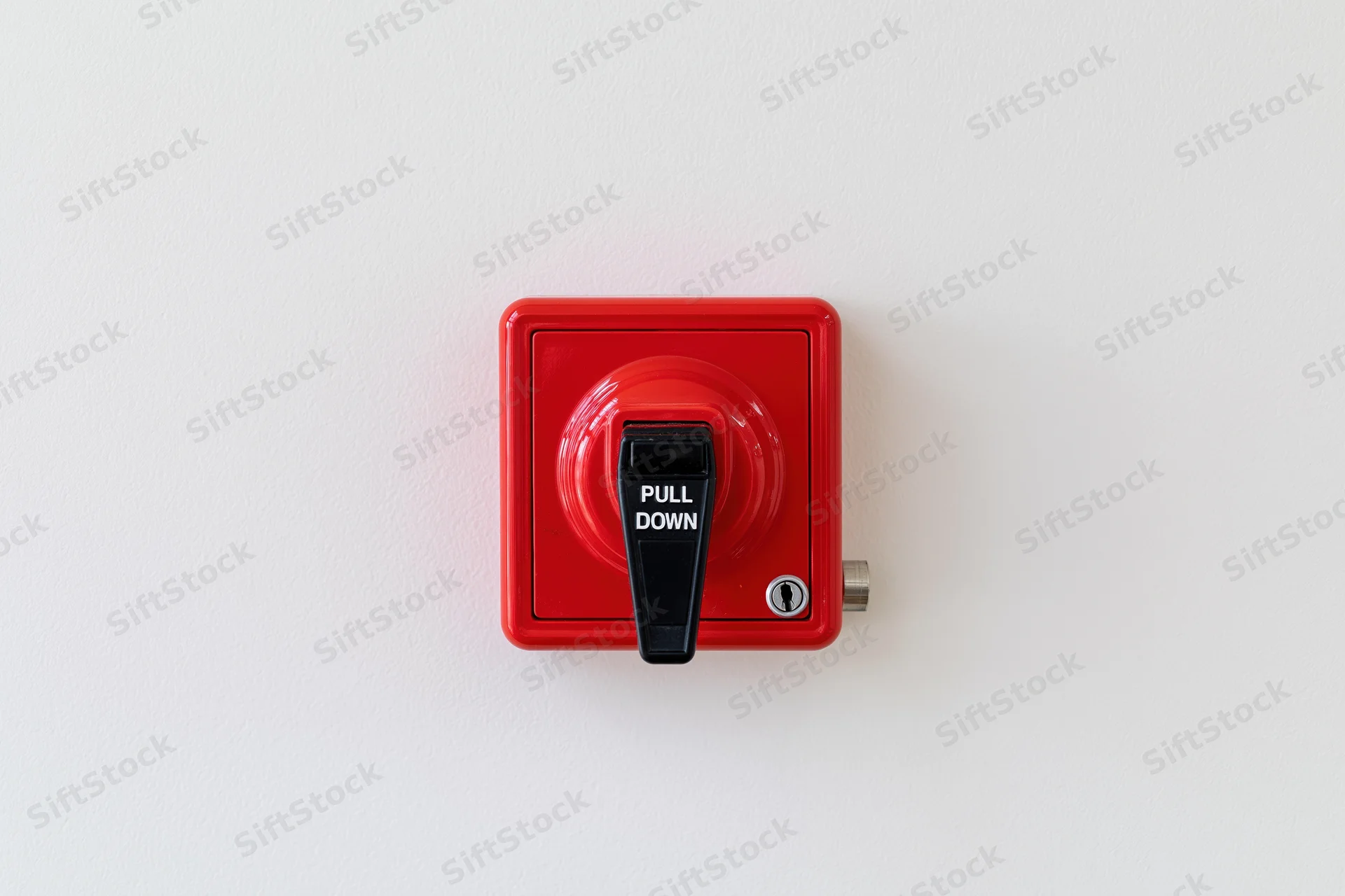 Red fire alarm pull station mounted on a white wall