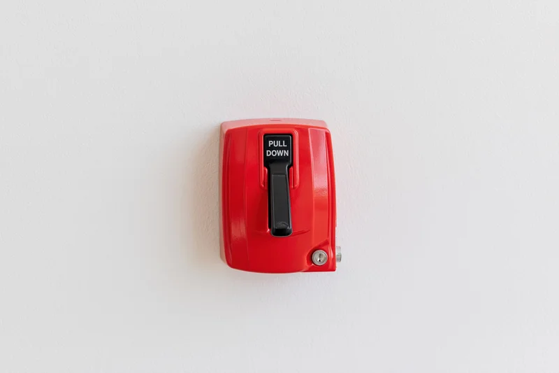 Red fire alarm pull station mounted on a white wall