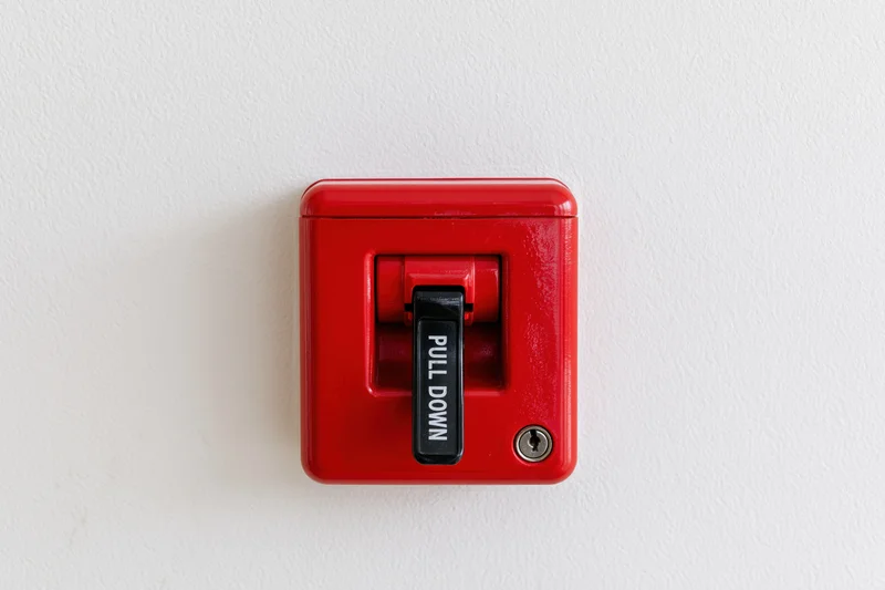 Red fire alarm pull station mounted on white wall