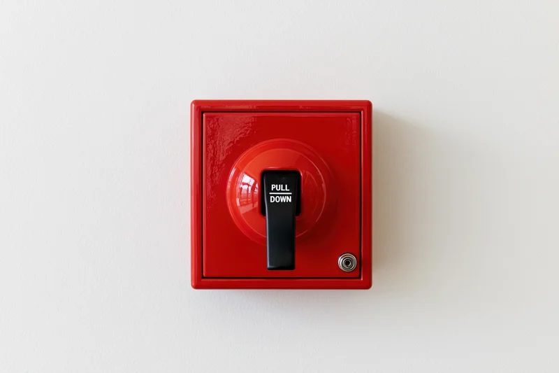 Red fire alarm pull station mounted on a white wall