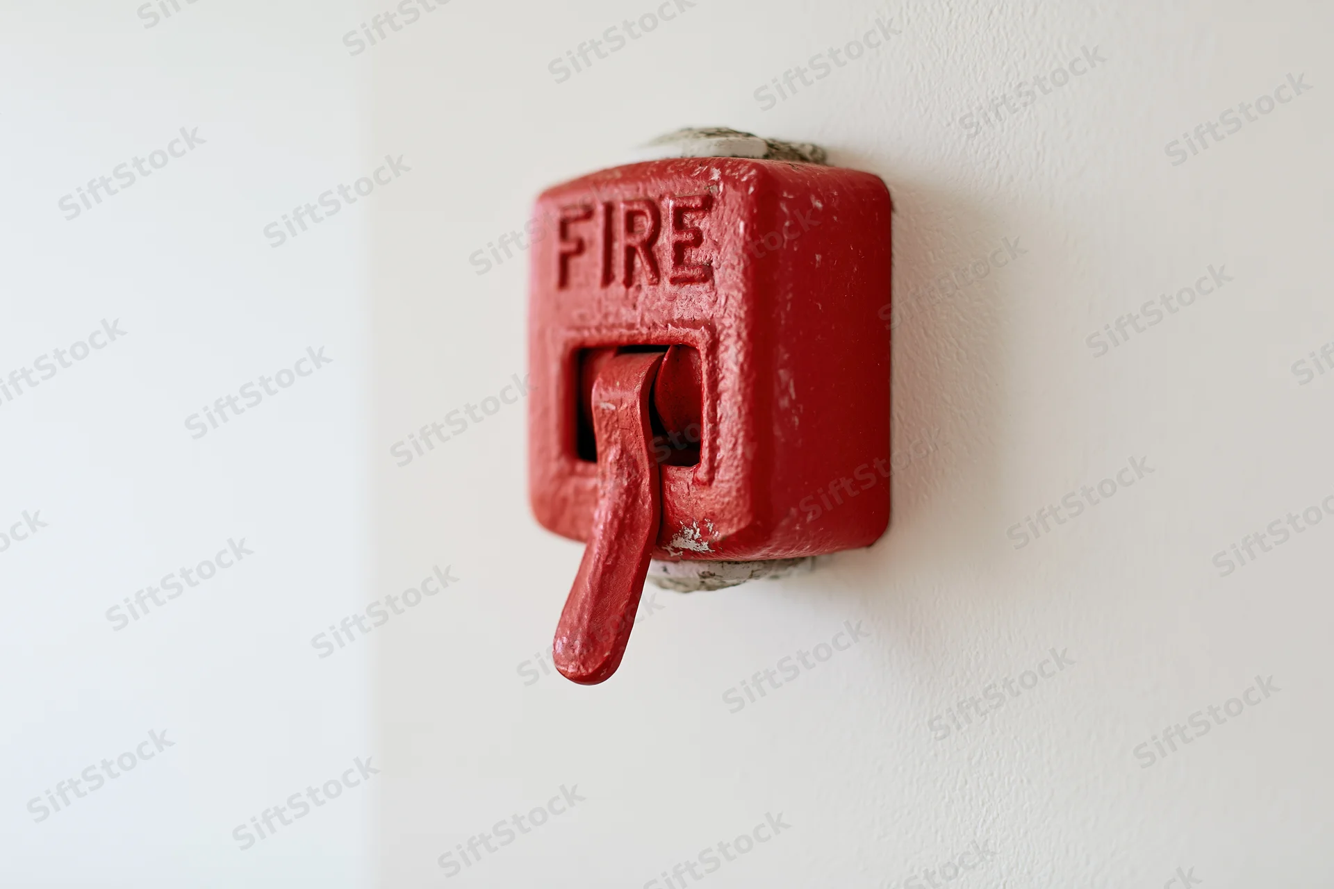 Red fire alarm pull station mounted on a plain off-white interior wall