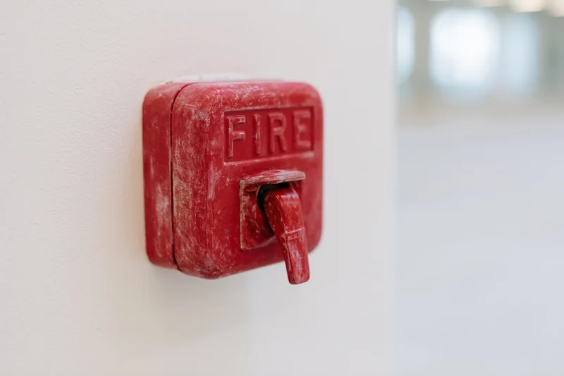 Red fire alarm pull station mounted on a white interior wall