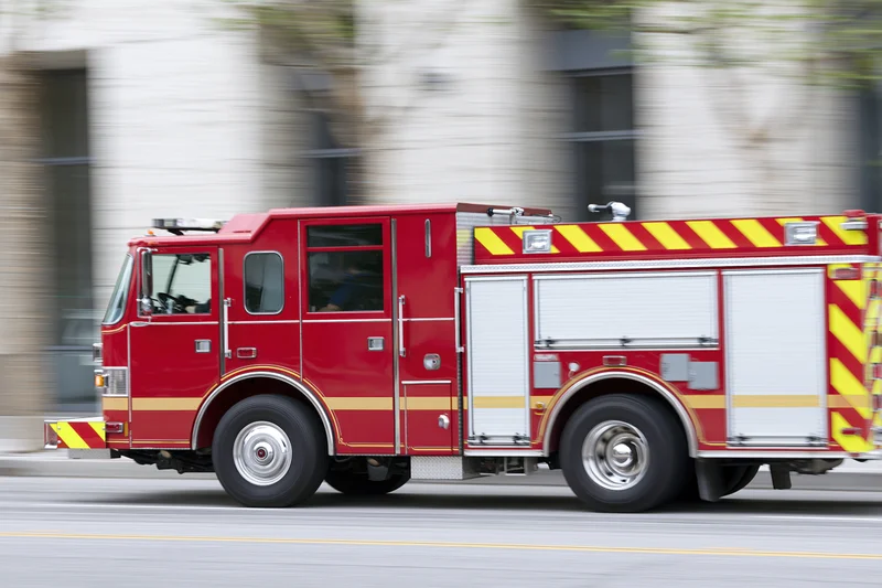 Red firetruck speeding down city street with motion blur
