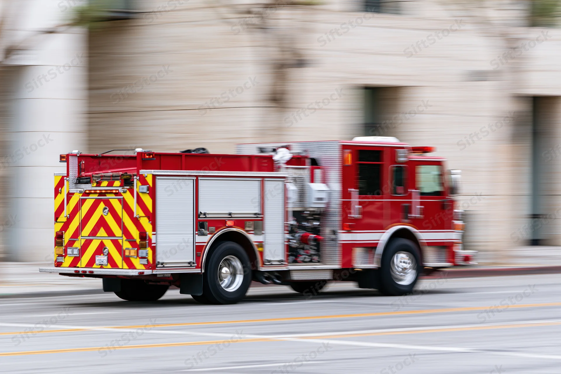 Red fire department engine truck speeding through city street with motion blur