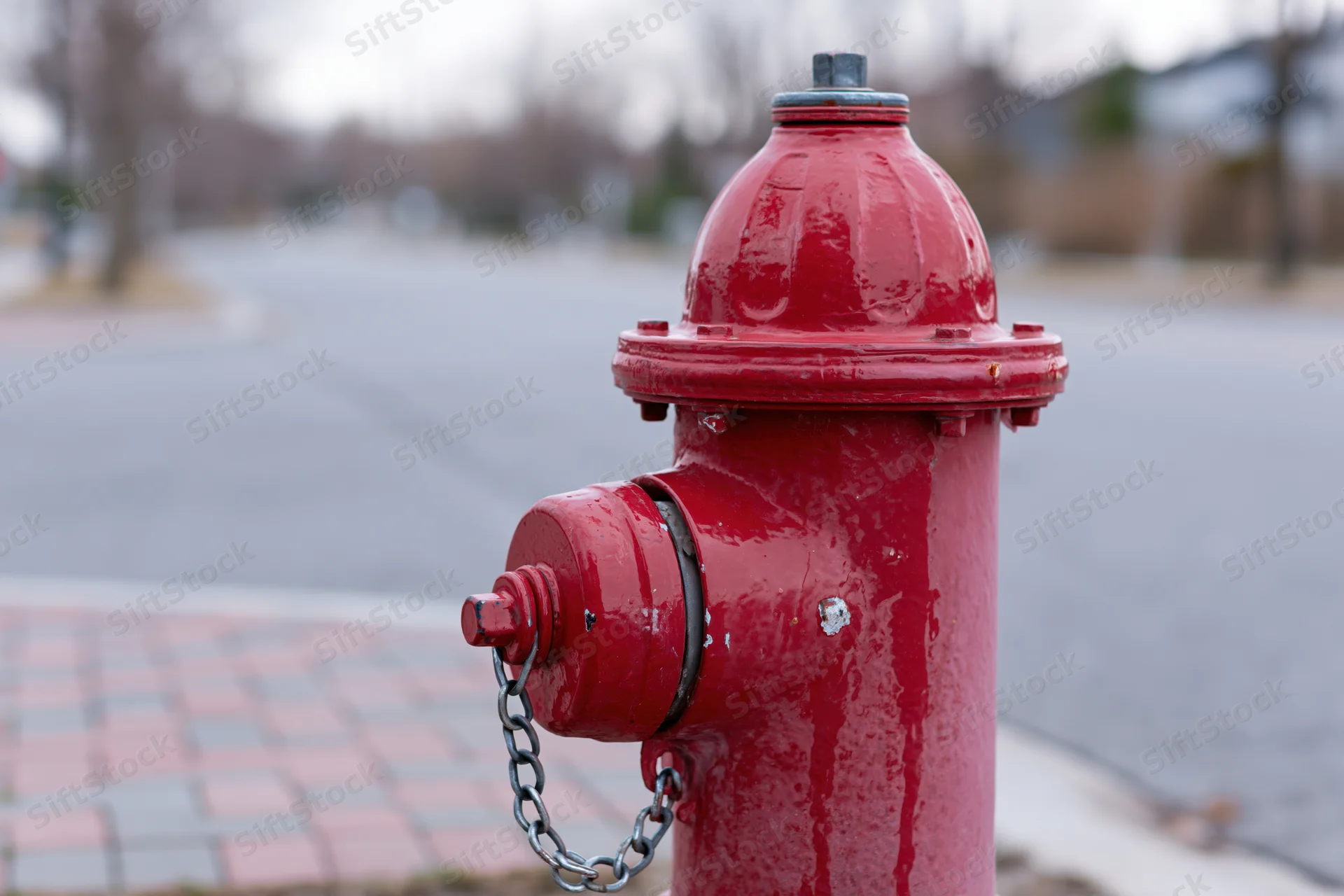 Red fire hydrant with chain attached, close-up on sidewalk near street