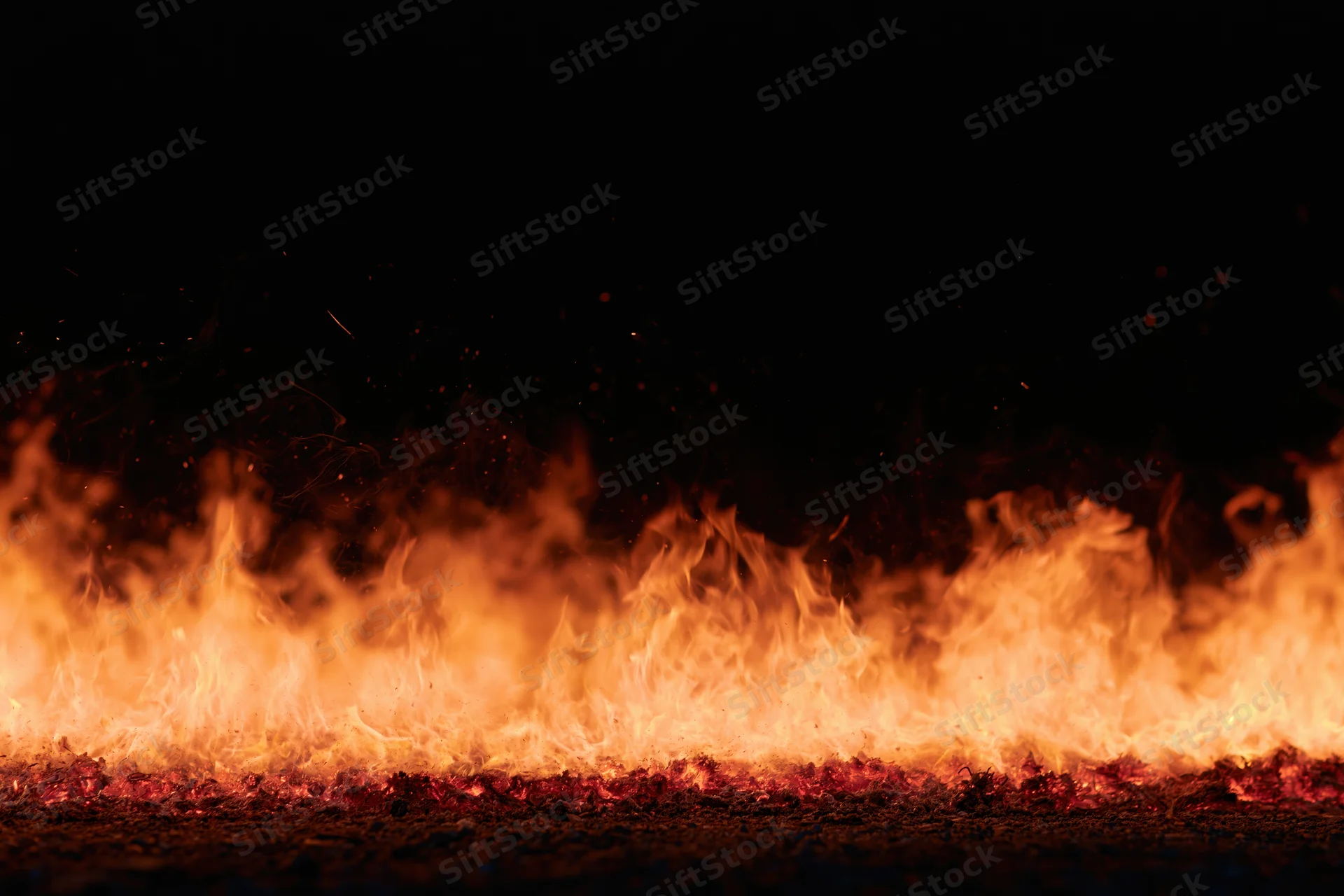 Intense flames burning across the ground at night