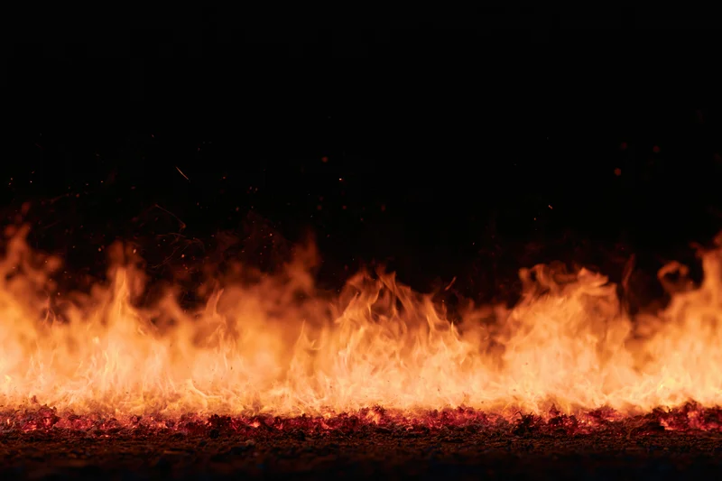 Intense flames burning across the ground at night