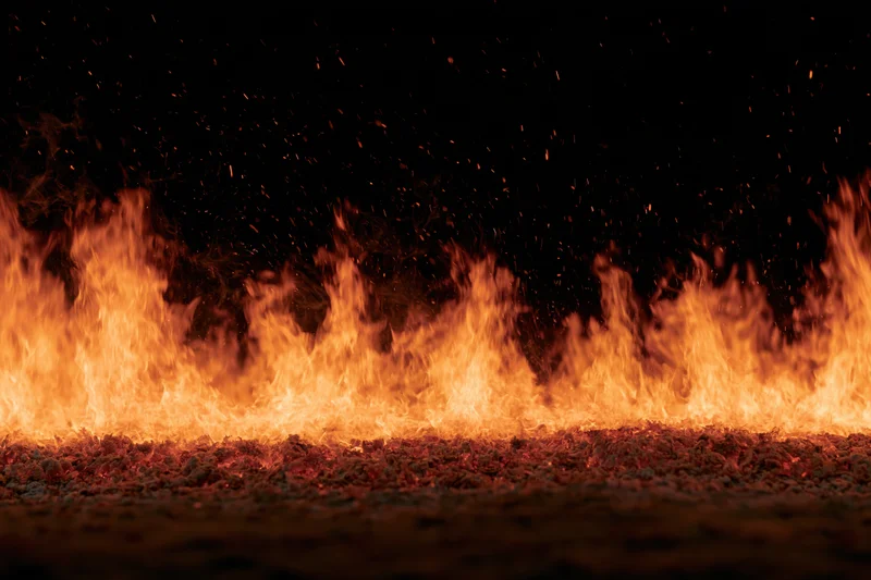 Row of intense flames burning across dark ground at night