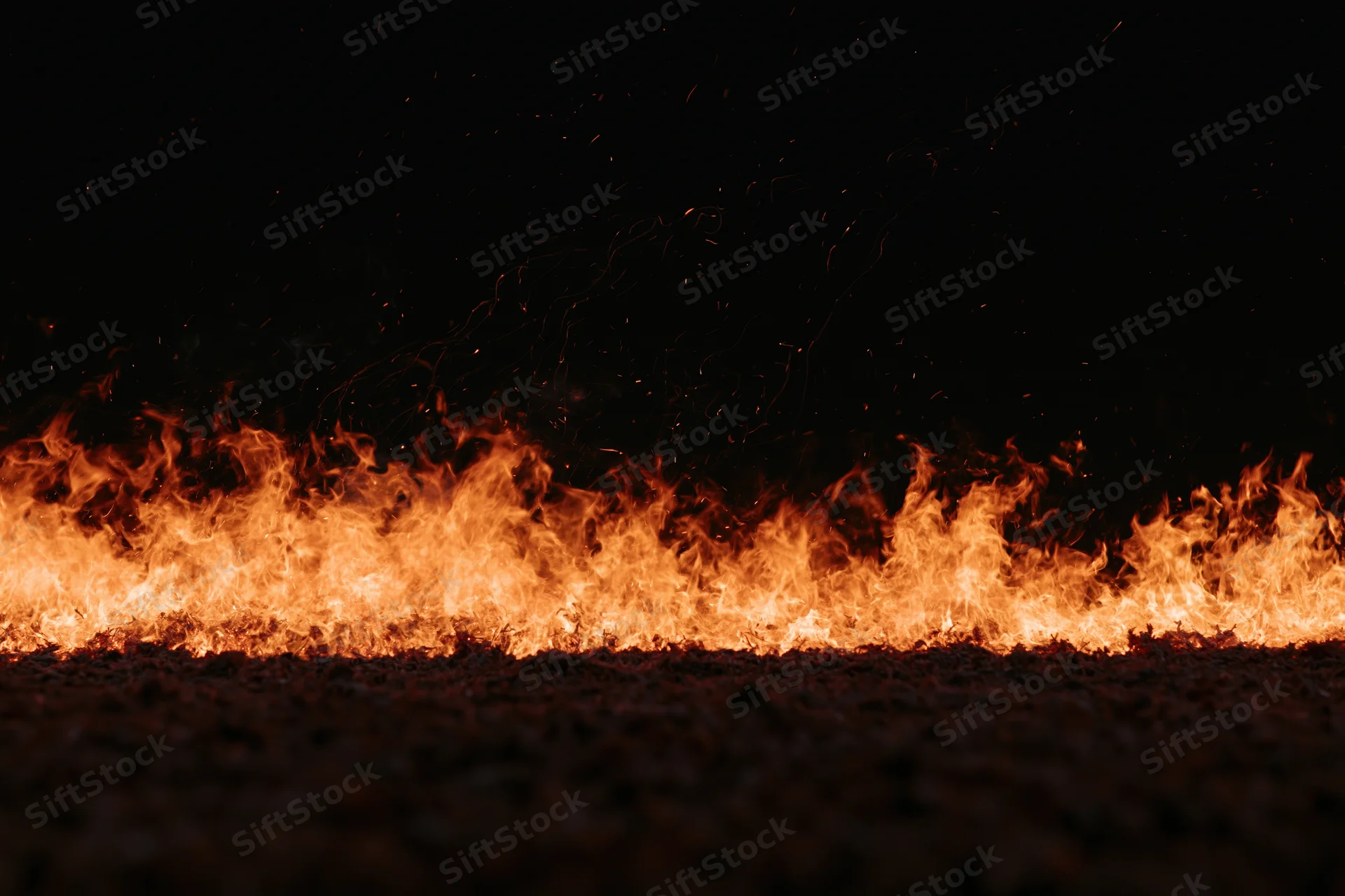Intense flames burning across the ground at night