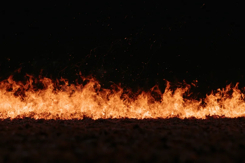 Intense flames burning across the ground at night