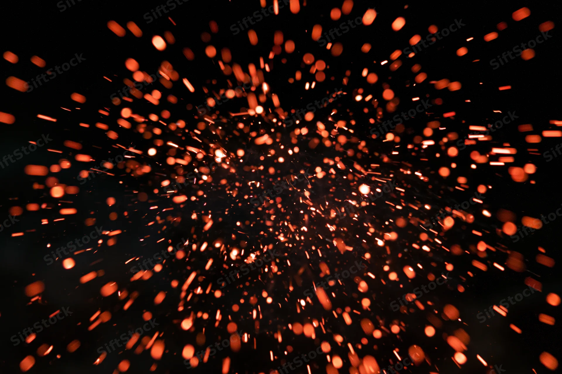 Glowing orange sparks bursting outward in dark night sky