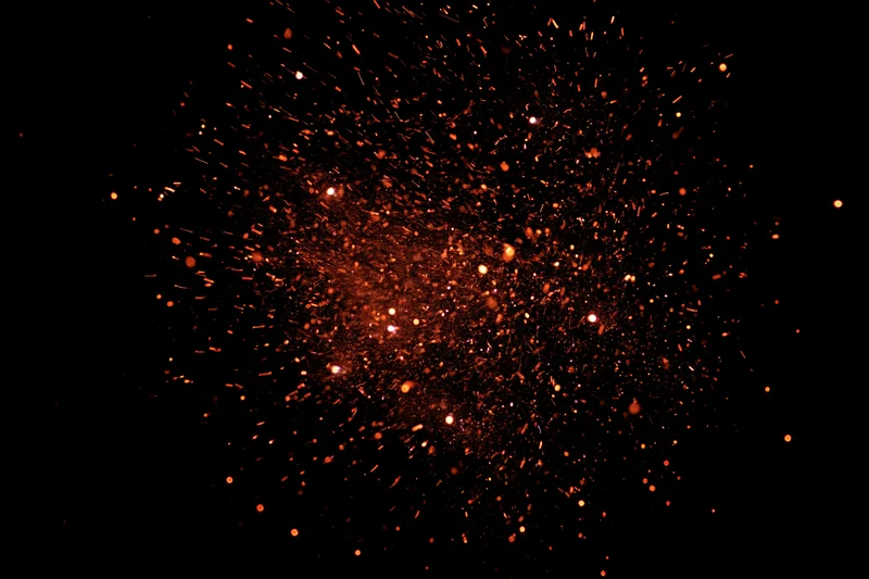 Glowing orange sparks bursting outward against a black background