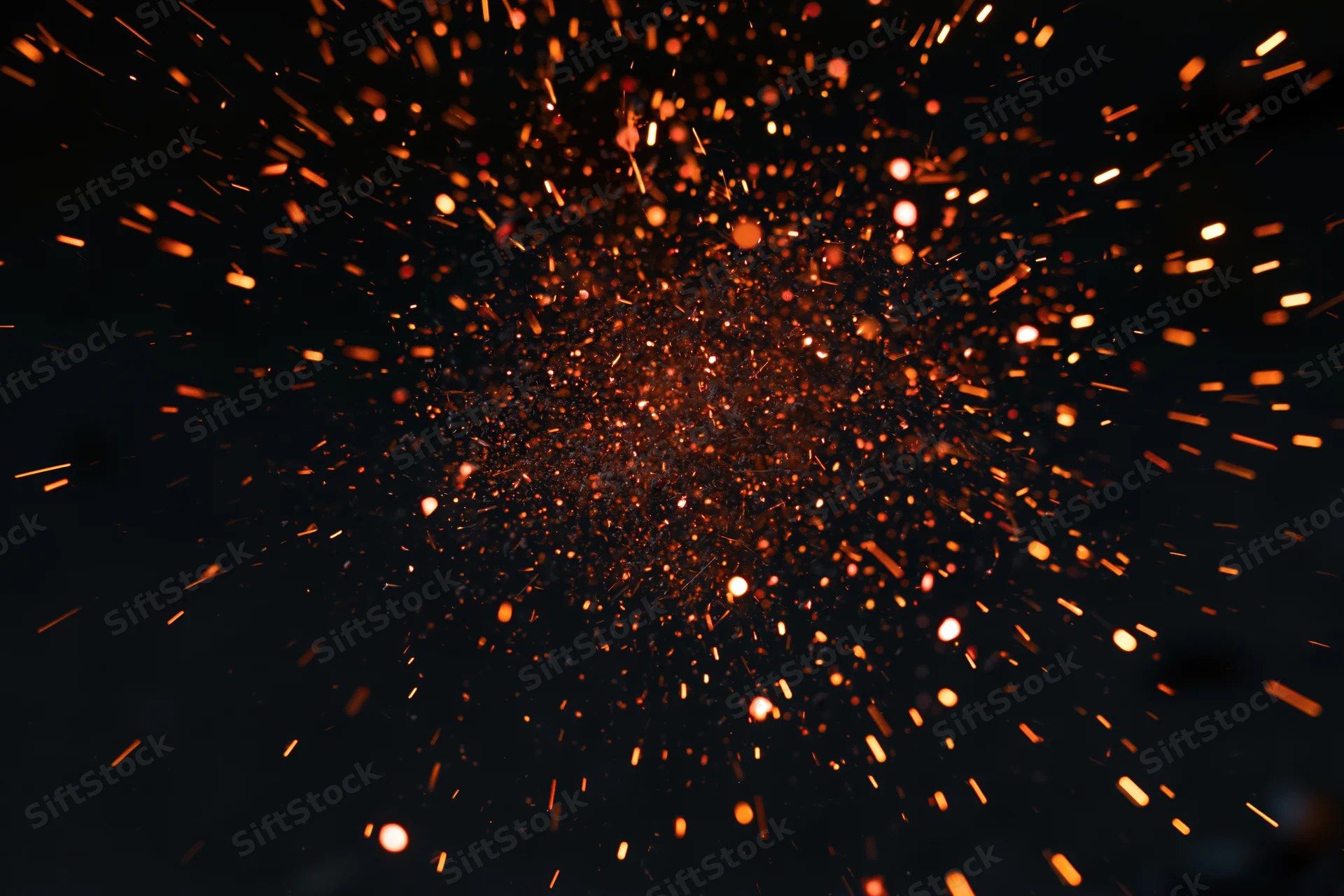 Glowing sparks and embers bursting outward in dark space