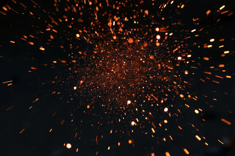 Glowing sparks and embers bursting outward in dark space