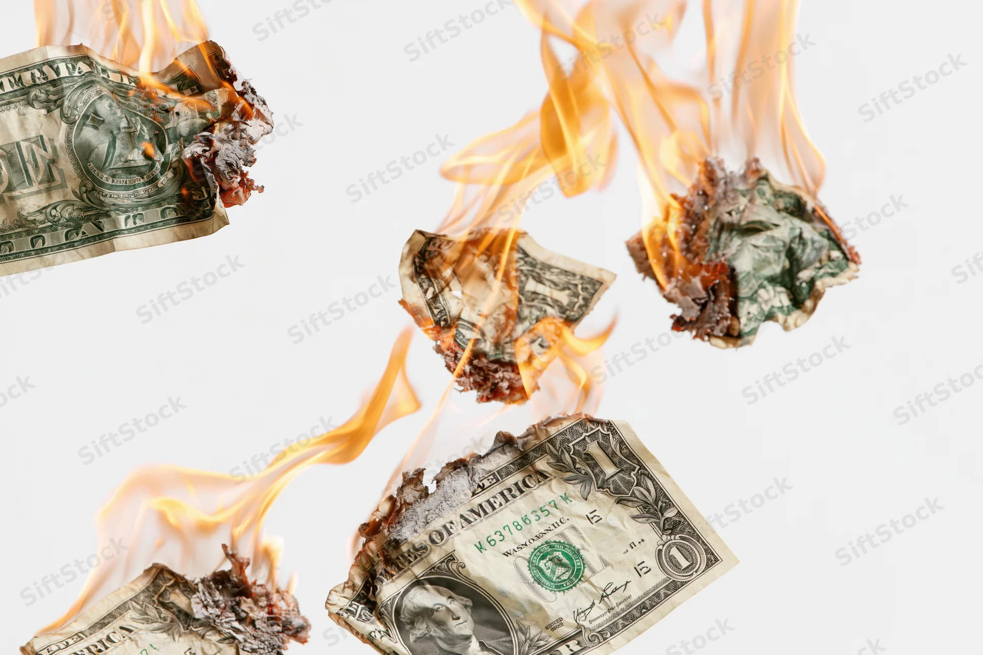 Burning one-dollar bills engulfed in flames against a white background