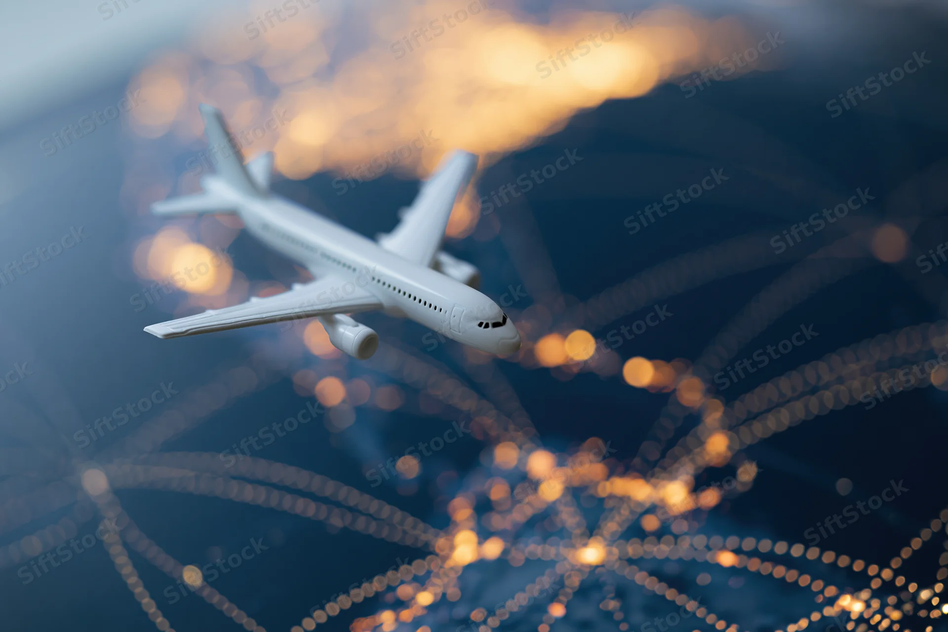 White model airplane flying over blurred bokeh lights representing global flight network