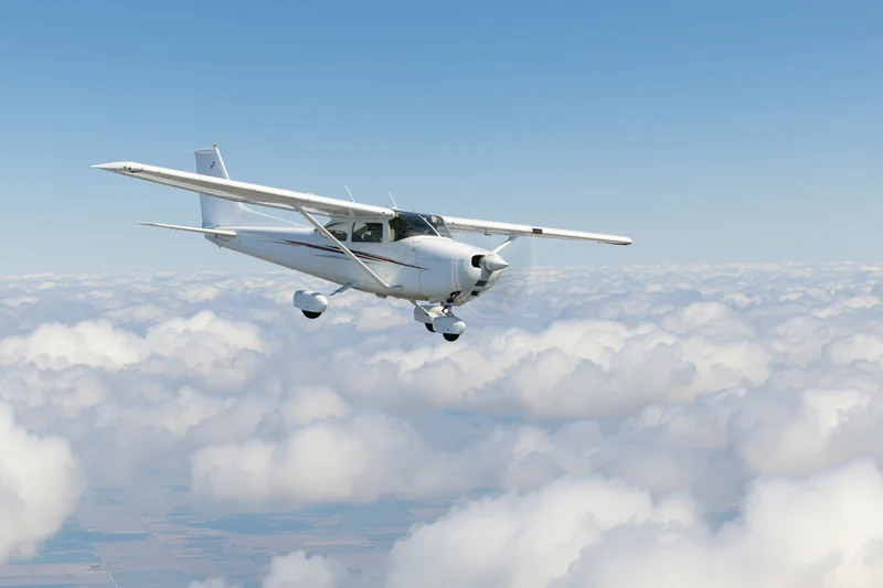 Small white single-engine propeller plane in level flight above cloud layer