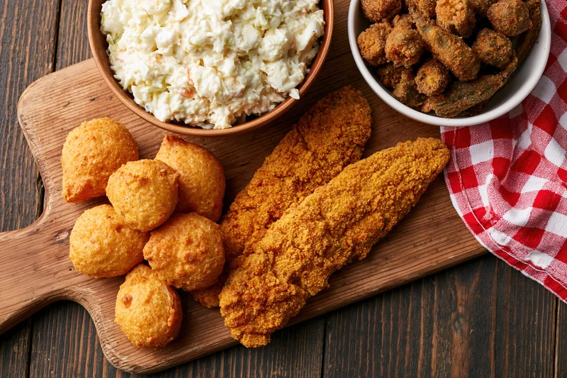 Fried fish and hushpuppies with coleslaw on a wooden serving board